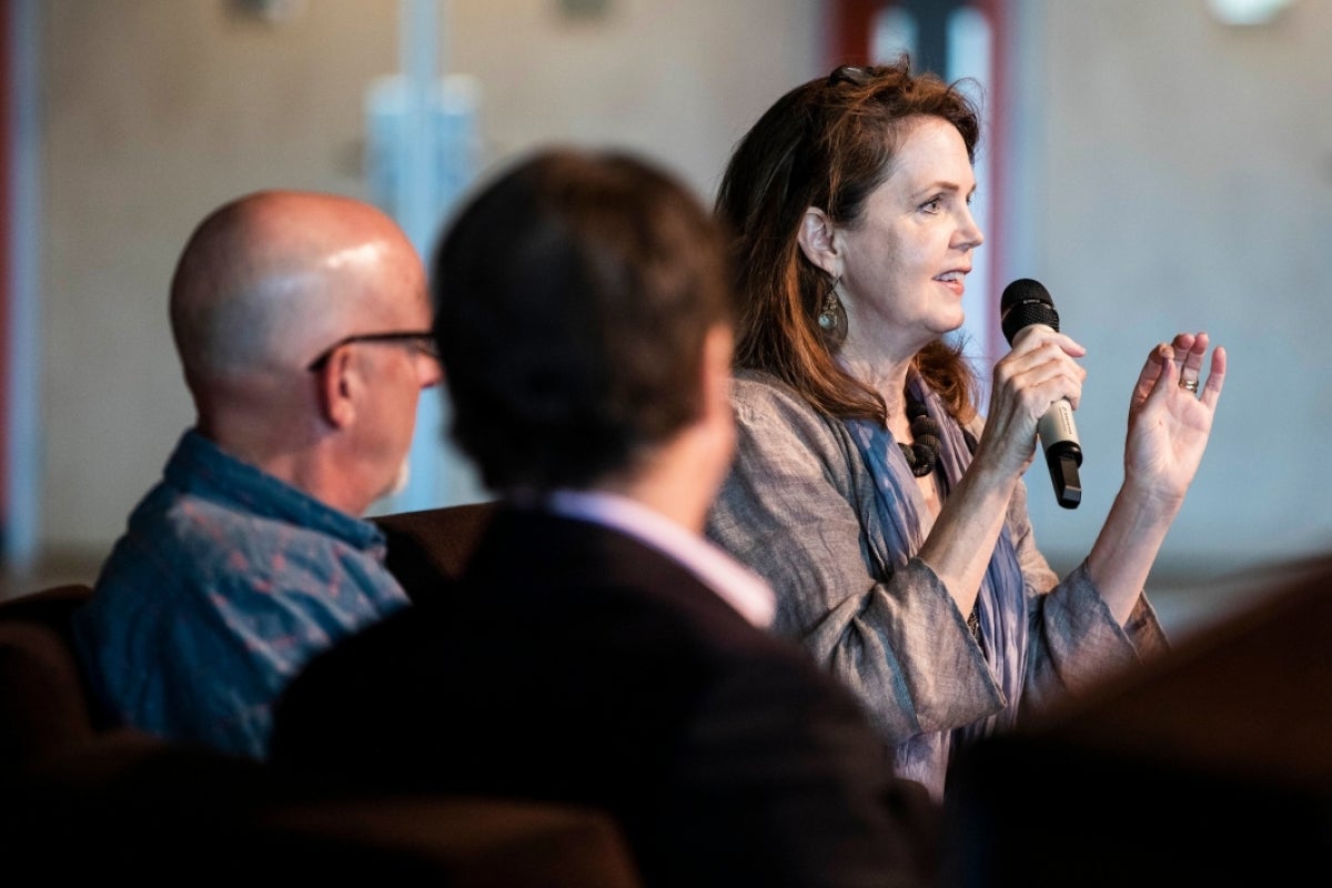 woman seated on a stage speaking into a microphone