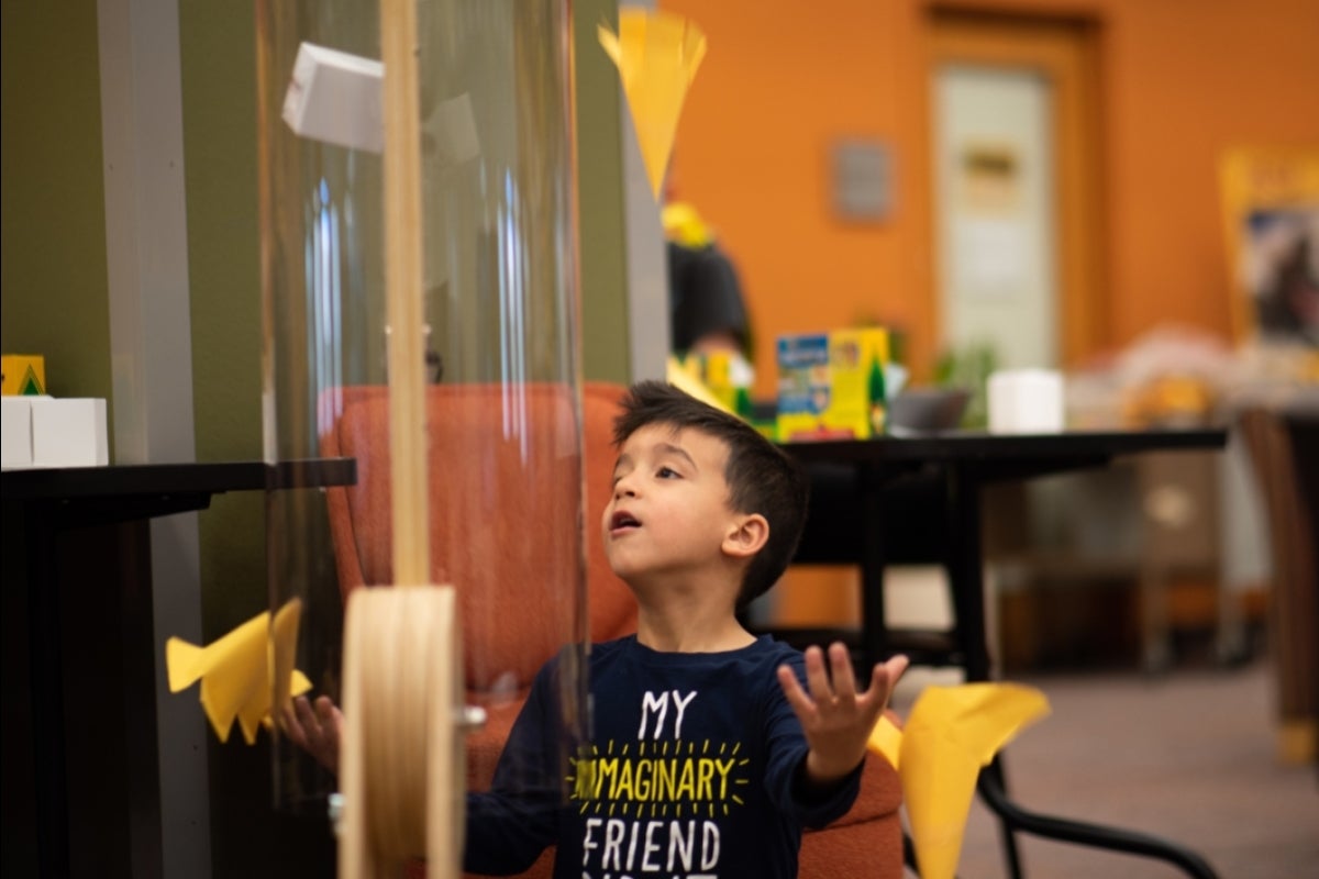 young boy looking up at a homemade helicopter as it flies