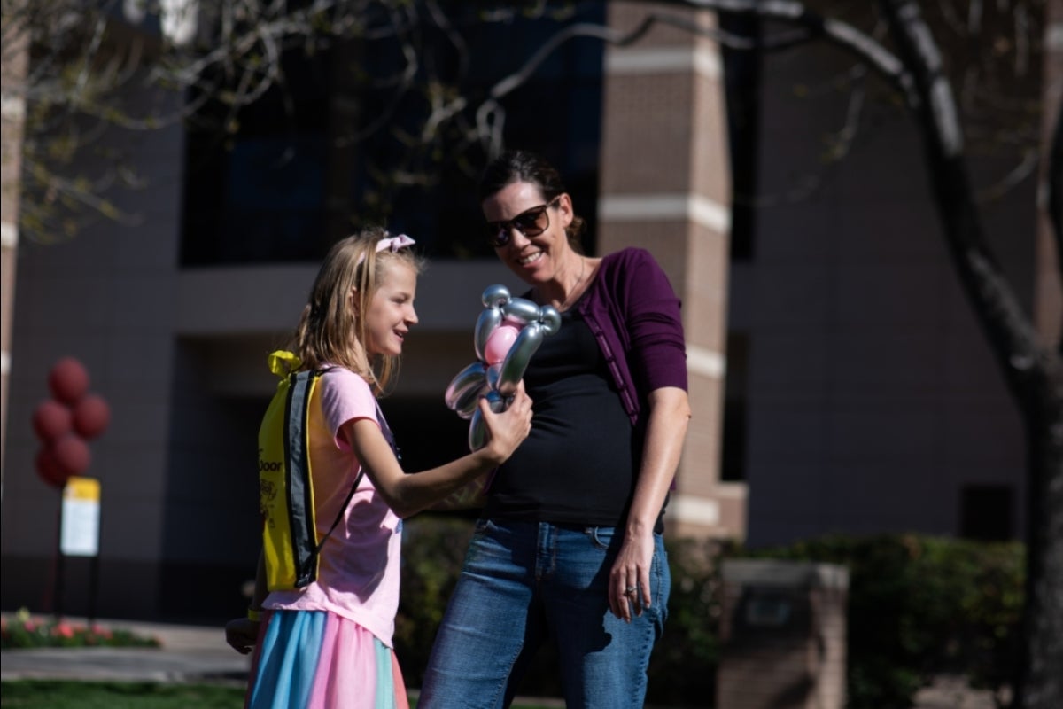 young blonde girl shows a silver balloon animal to her mom