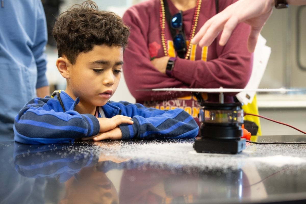 young boy watches a science experiment