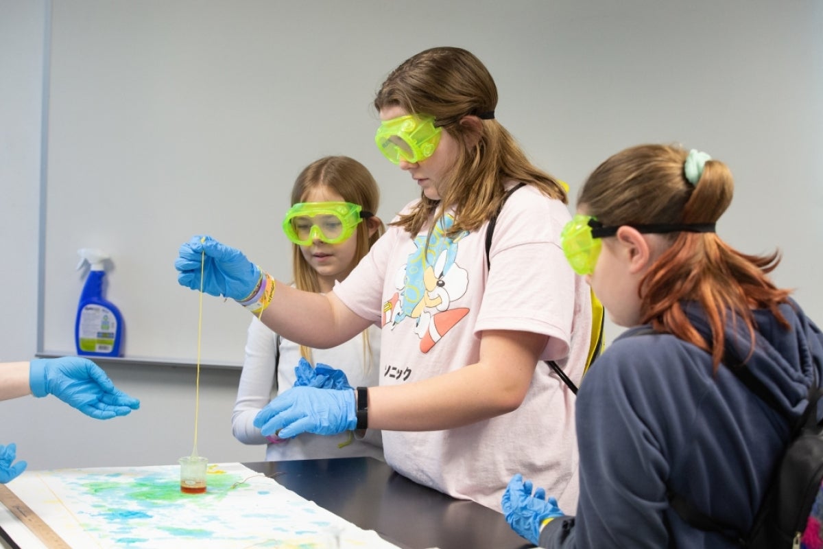 students wearing goggles and gloves mix solutions to make nylon