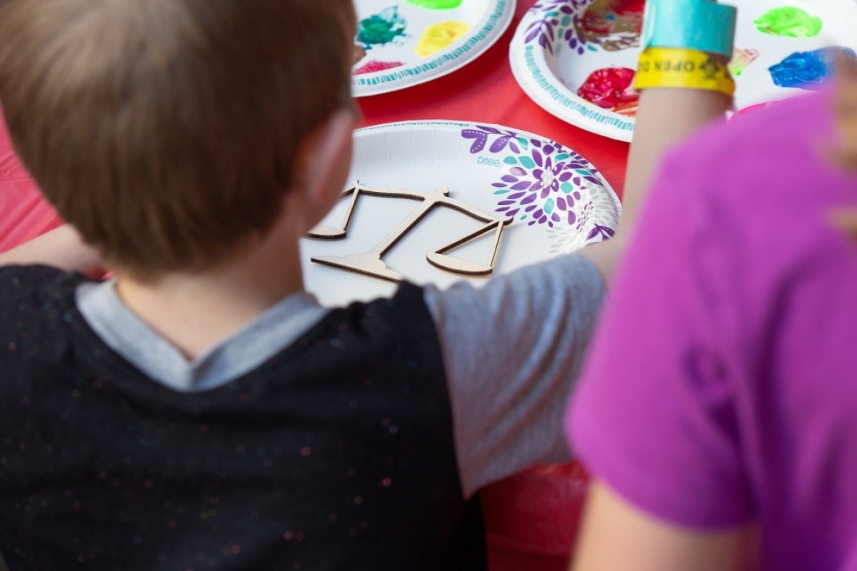 little boy paints a cardboard scales of justice cutout