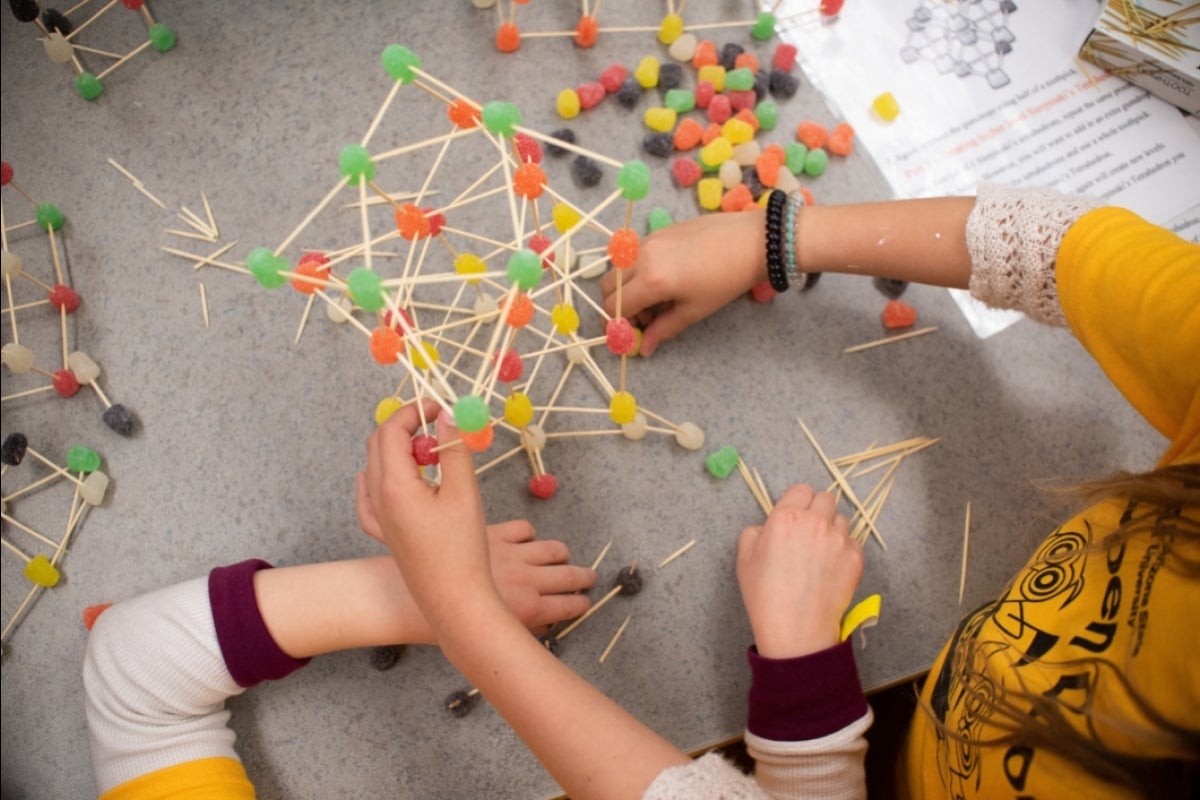 people constructing items out of toothpicks and gumdrops