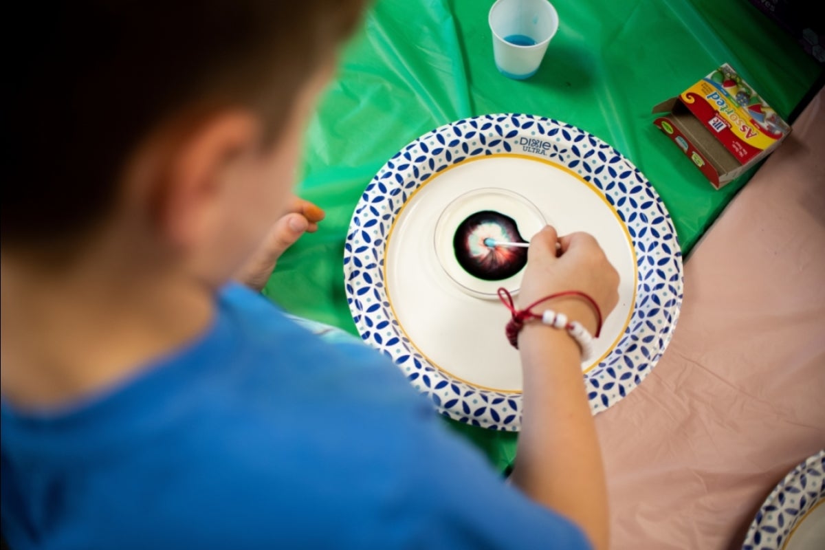 student does a science experiment with dish soap and dye