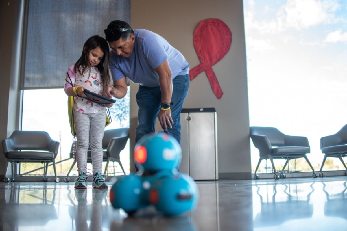 father leans down to show his daughter remote control device