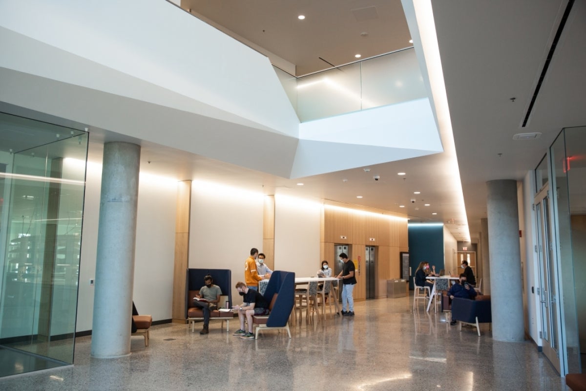 Student researchers work in a breezeway on various tables and lounge chairs