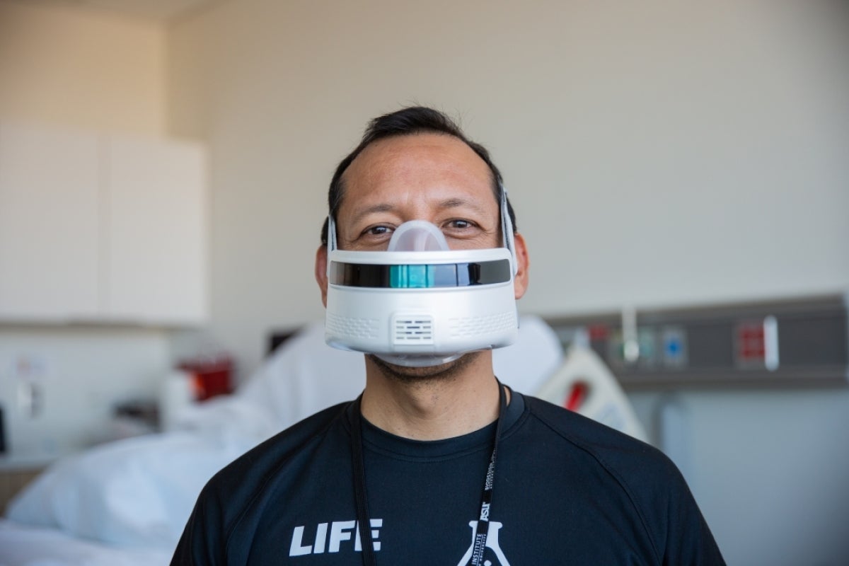 A man wears a breathing apparatus in a demonstration hospital room