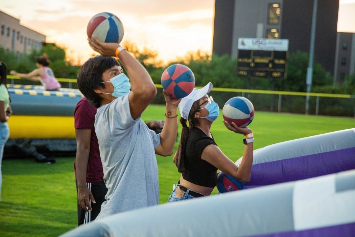 Masked students playing a basketball carnival game