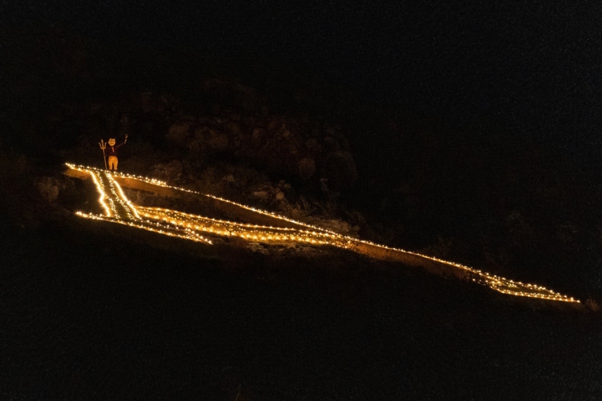 Sparky the ASU mascot stands at the top of the light-lined giant A on A Mountain at night