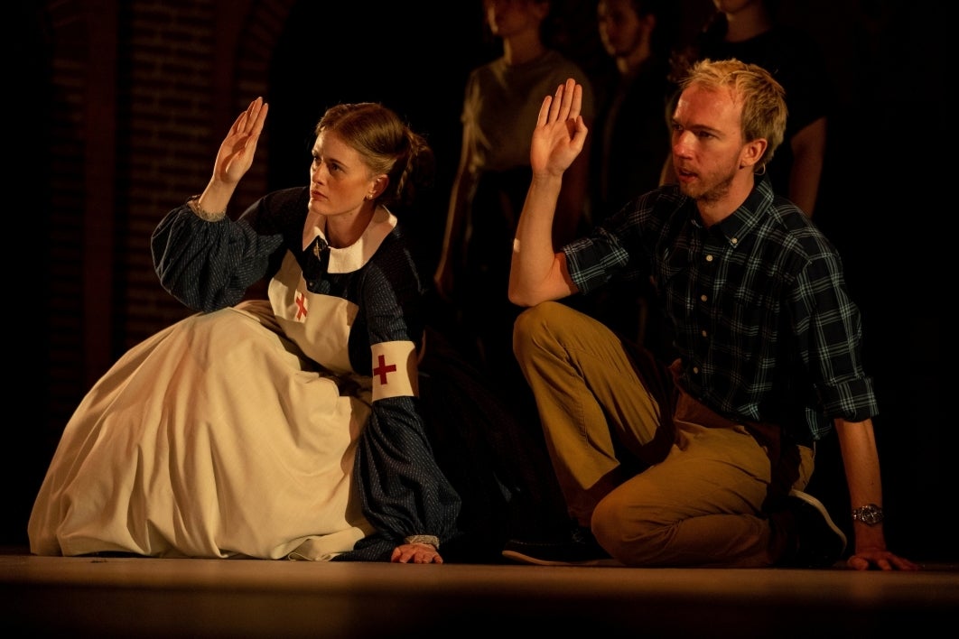 two people kneeling with hand raised in 