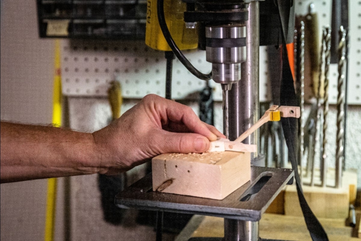 man drilling small hole into piano hammer