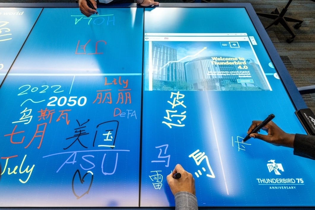 Hands holding styluses write on an electronic touch table