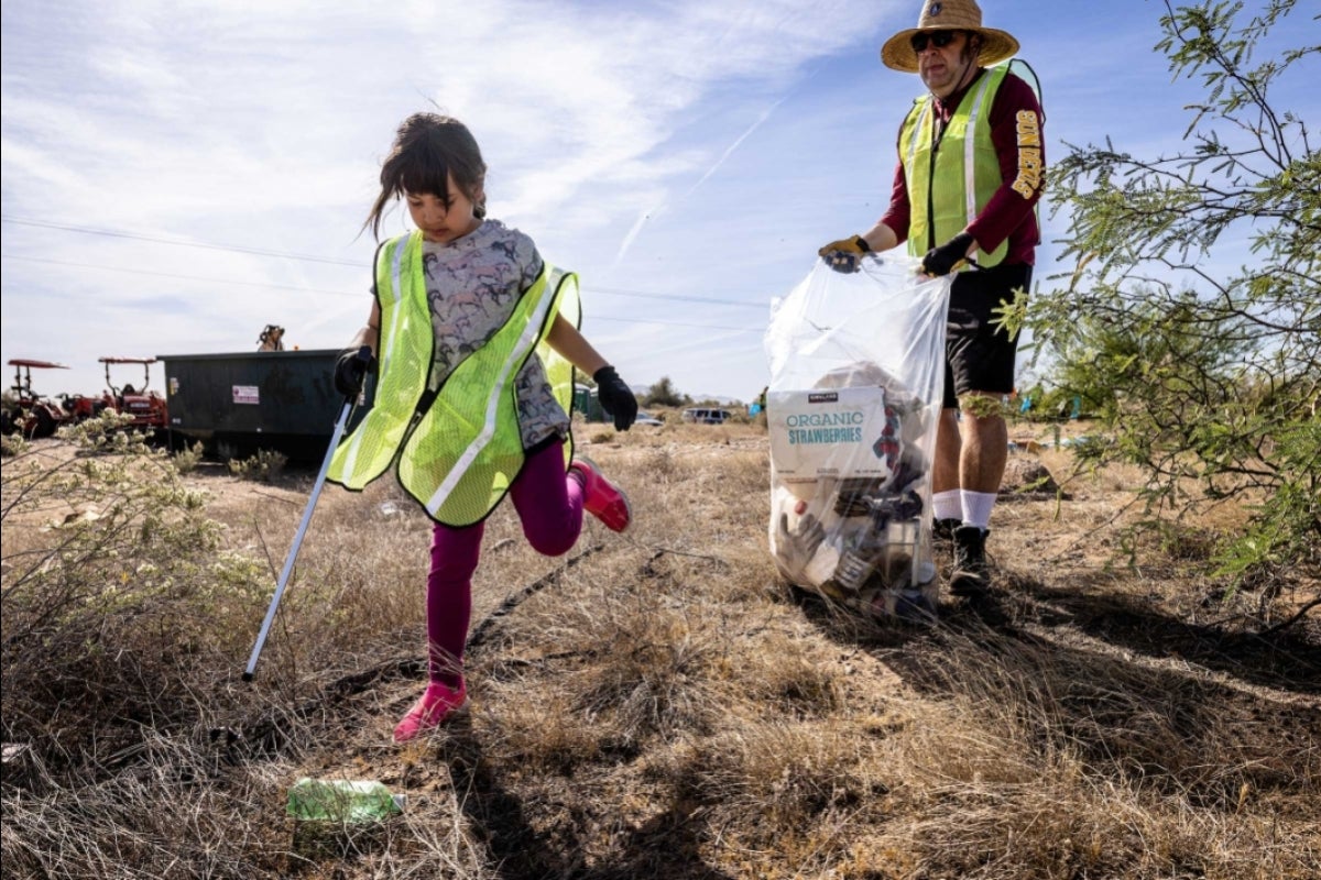 Girl picking up trash with her father