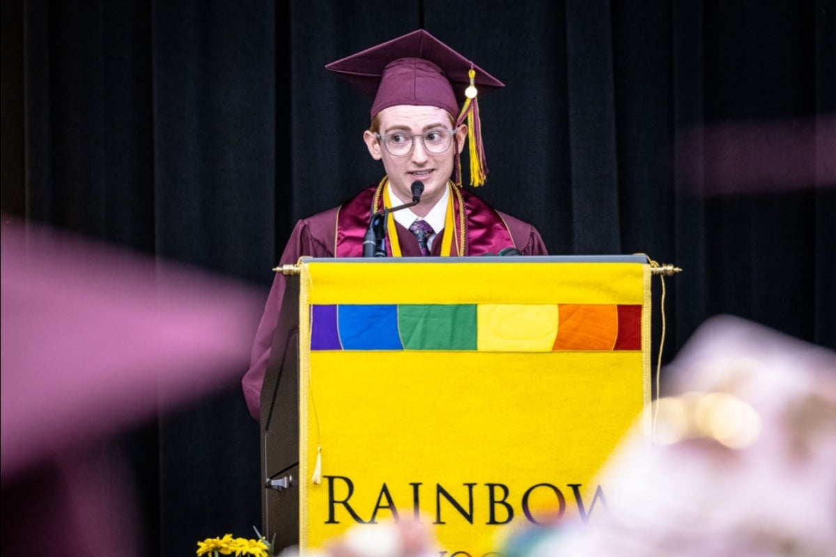 A young man speaks behind a lectern with a 