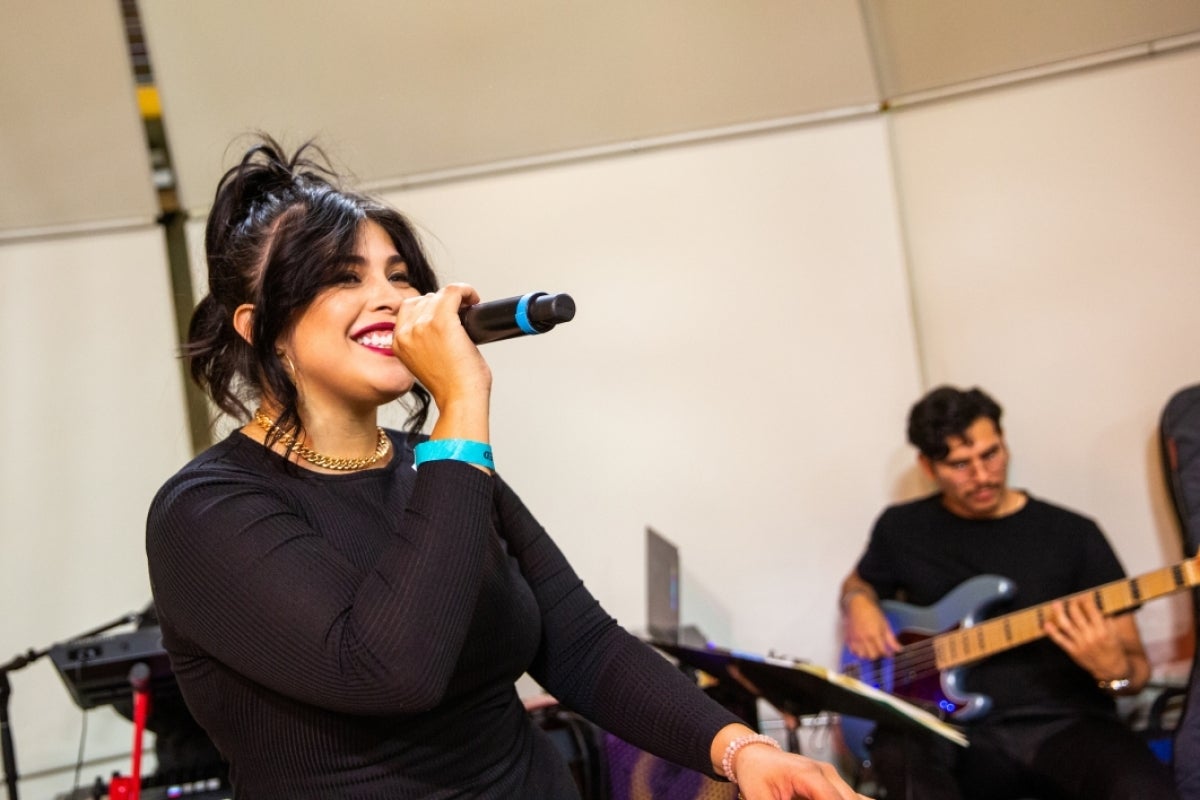 Woman in band singing with man playing electric guitar behind her