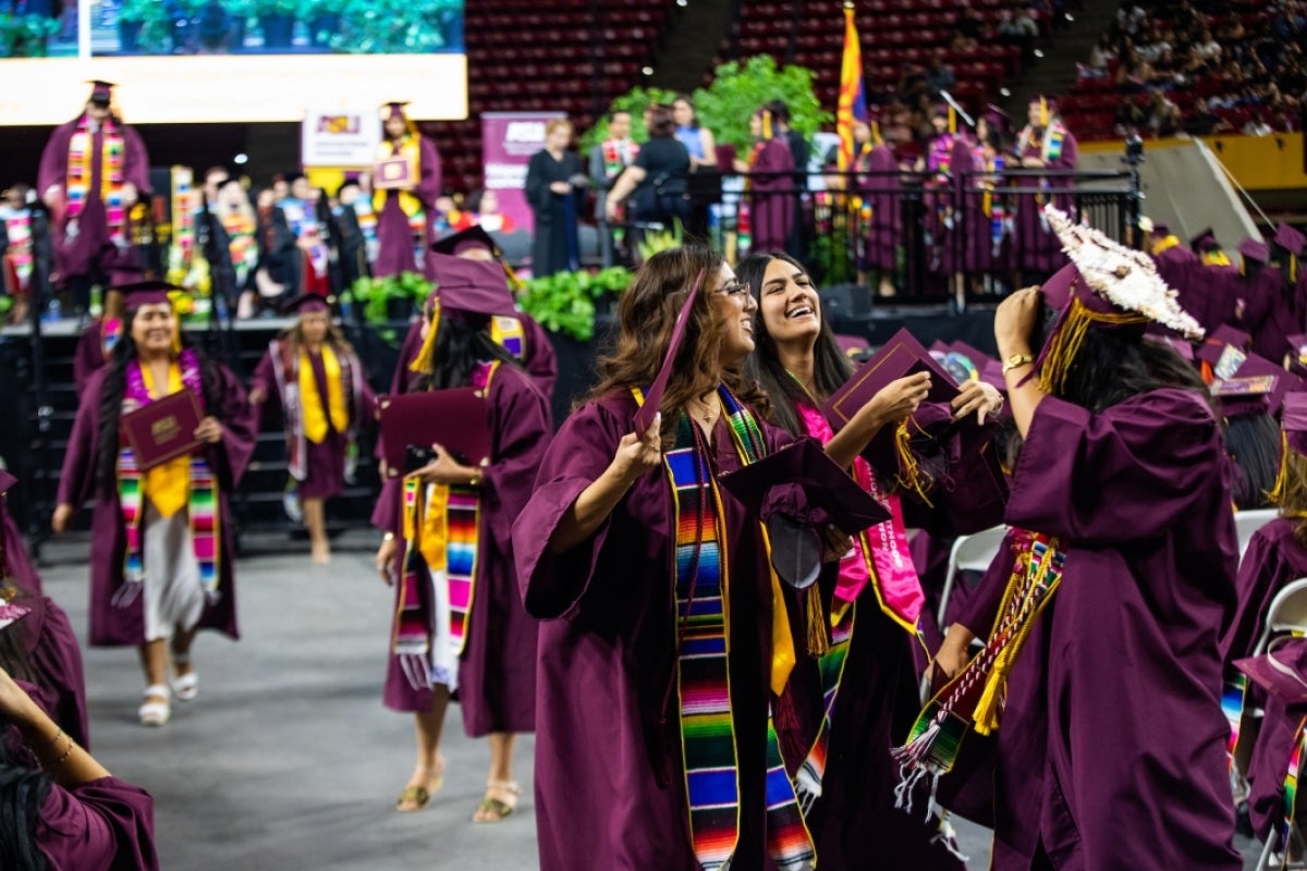 Three female graduates chatting in aisle during Hispanic Convcocation