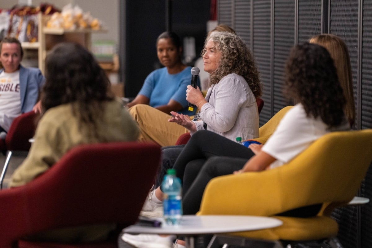 Woman on panel on stage speaks into microphone