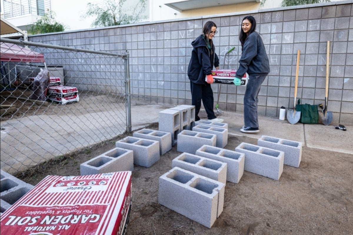 Two students carrying a bag of soil