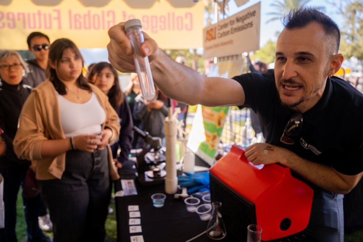 Man hold out a test tube during homecoming block party