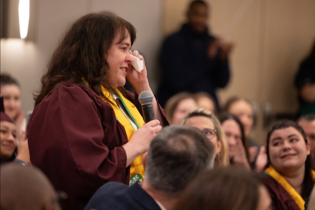 Woman speaking in audience and holding tissue up to eyes