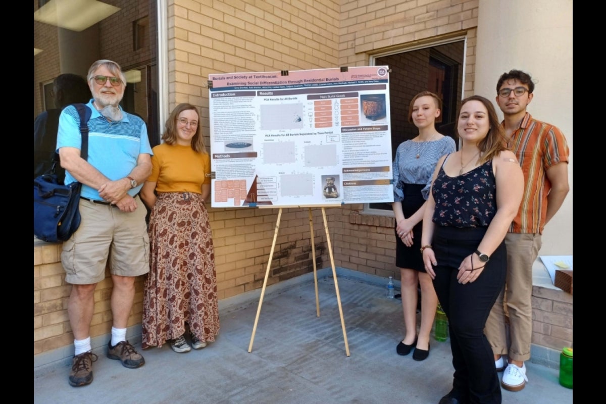 Students standing next to a poster board.