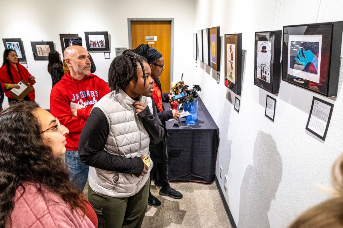 People look at art hanging on walls during exhibit opening