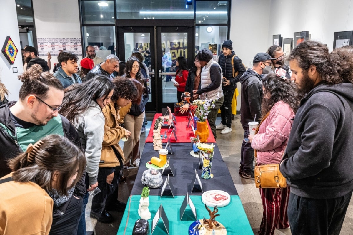 People look at pieces during an art exhibit opening on the West campus