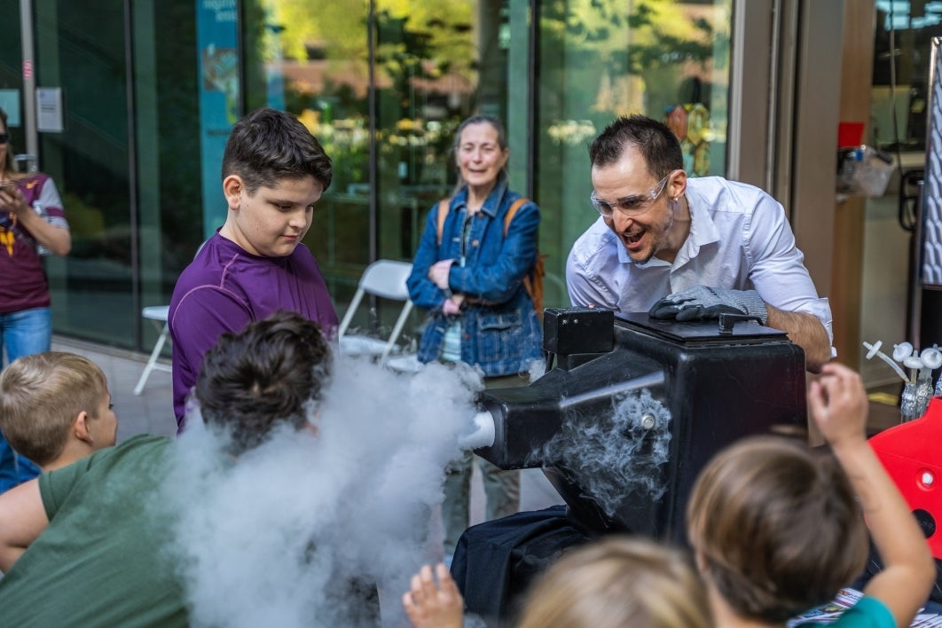 Man blowing fog with a machine toward crowd