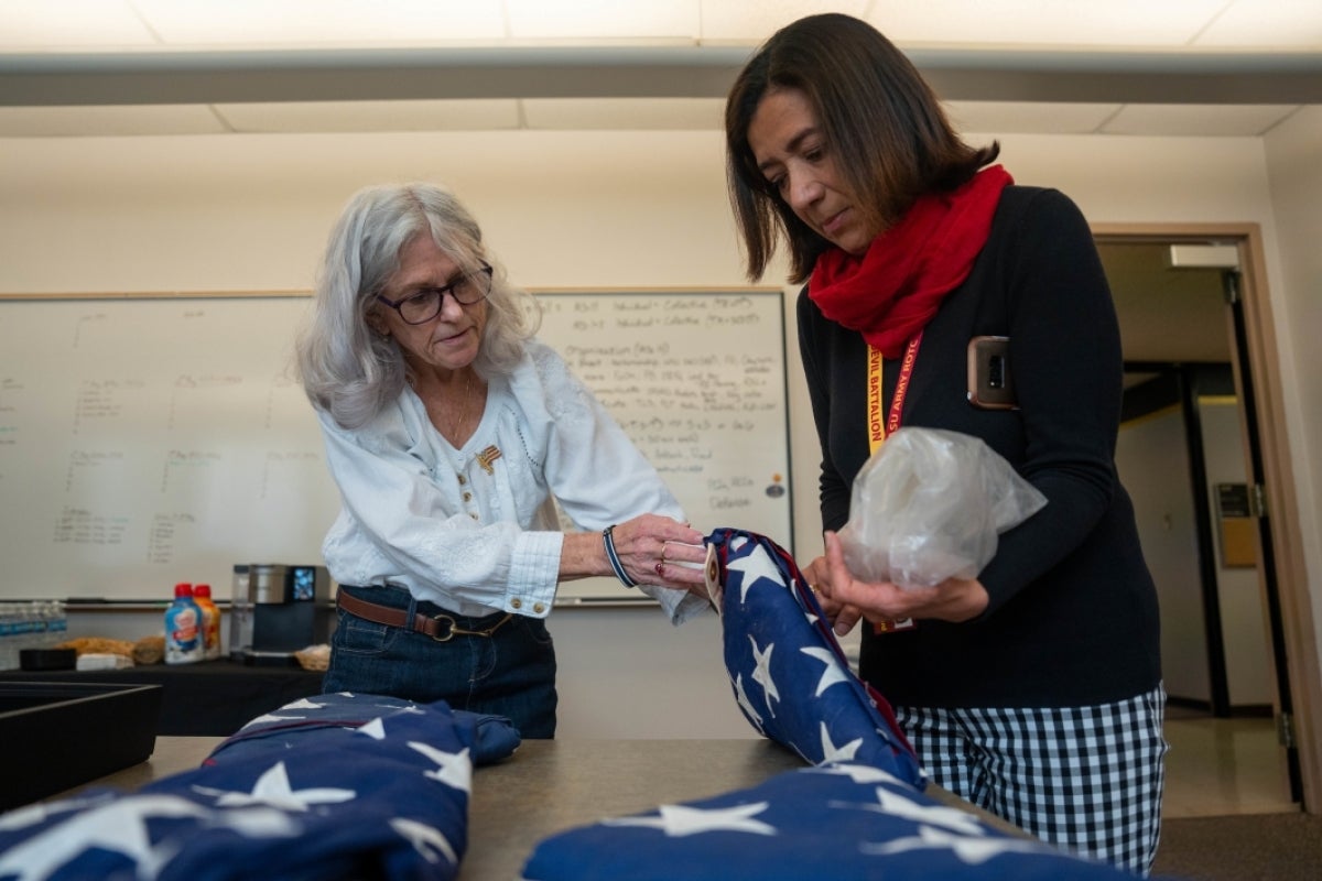 Two people look at four folded US flags