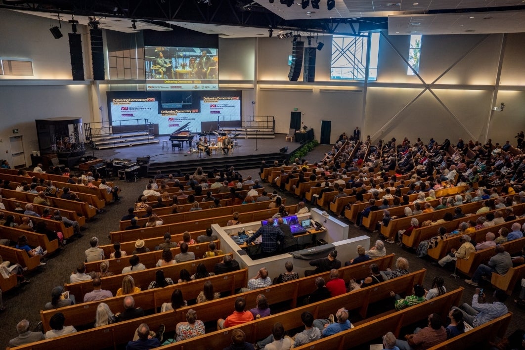 View of large audience in church listening to talk on stage