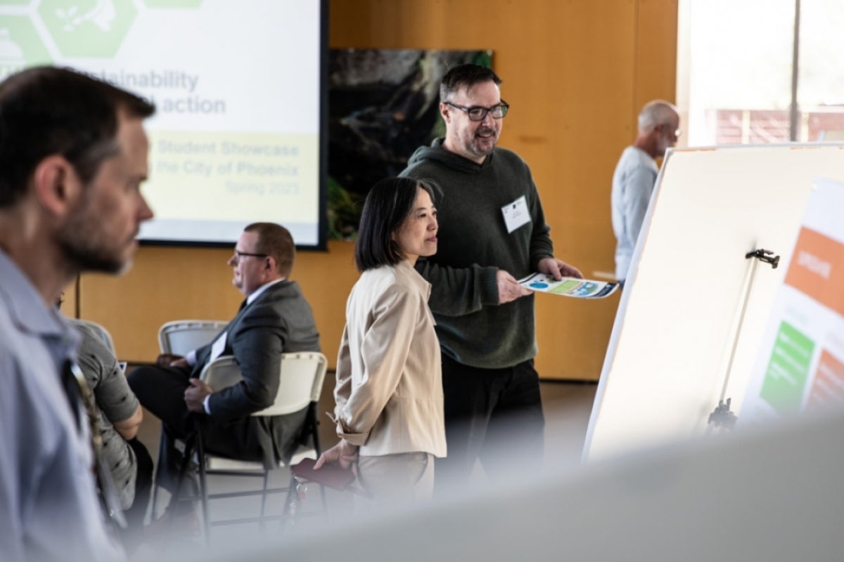 Two people look at poster board.