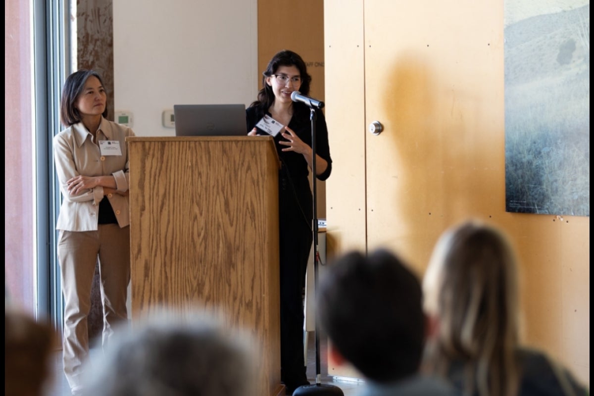 Student giving presentation at lectern with professor next to her