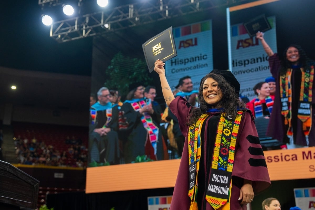 Graduate crossing stage holding diploma in air