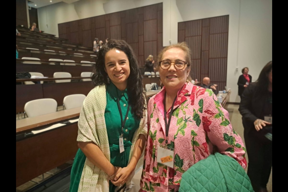 Two women smiling for the camera in an auditorium.