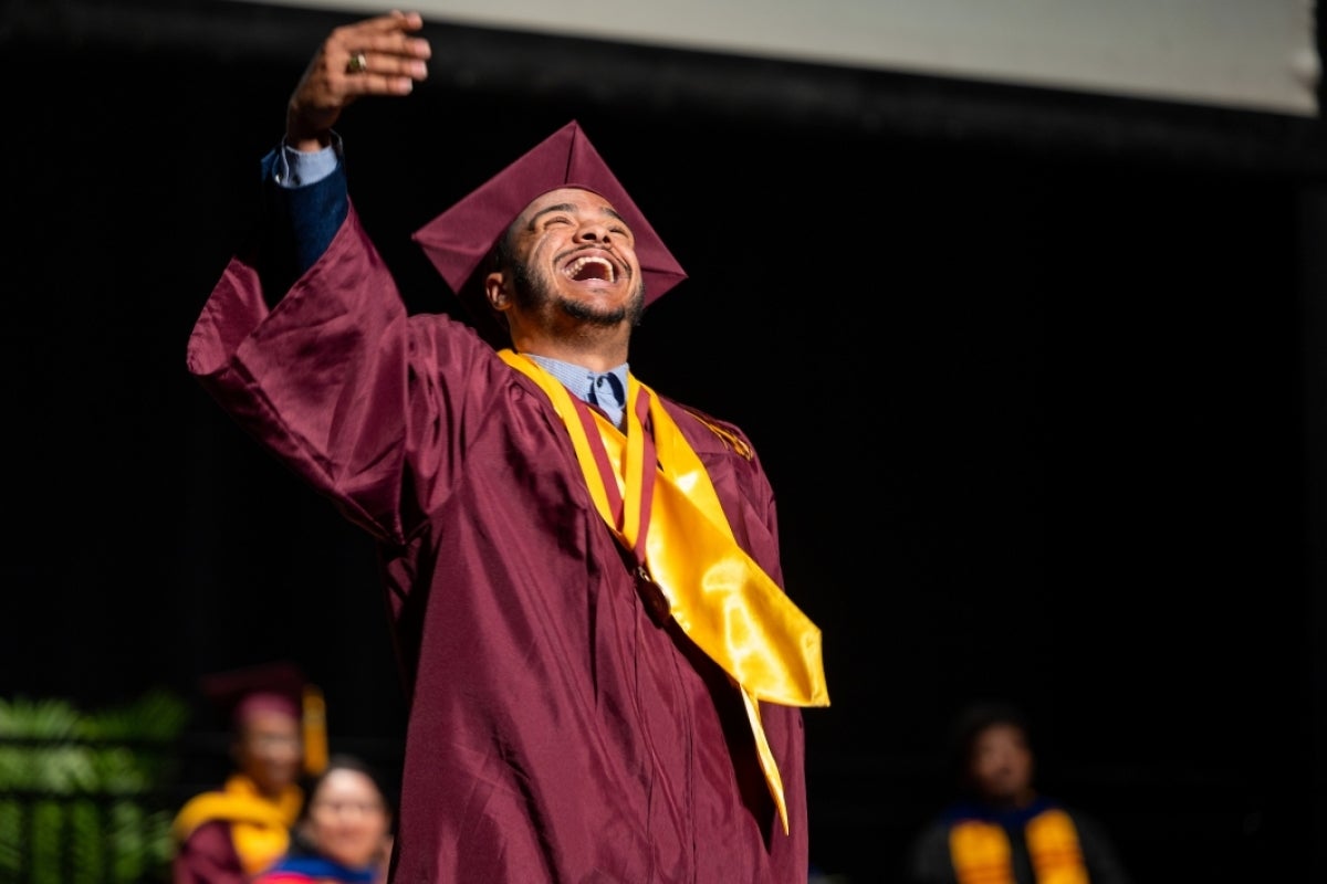 Graduate looking up and smiling as he crosses stage at convocation