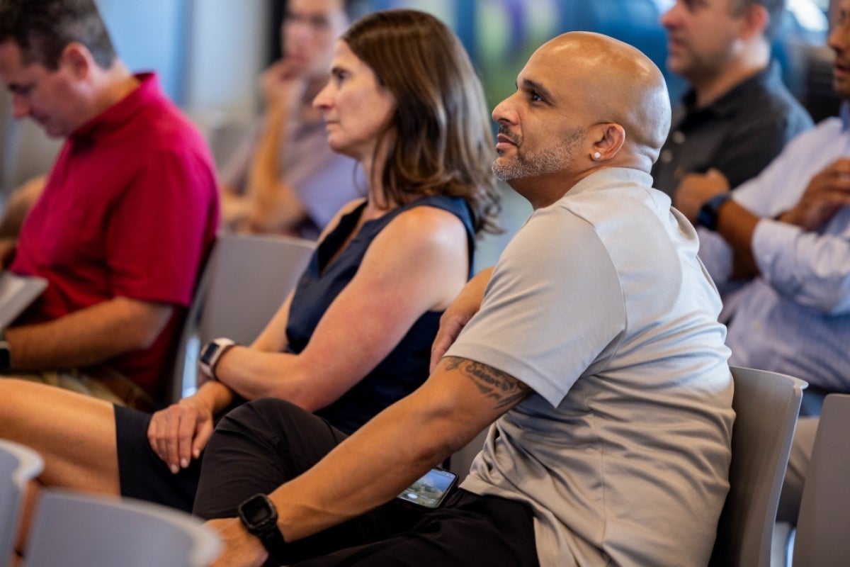 A man in an audience listens to someone speaking