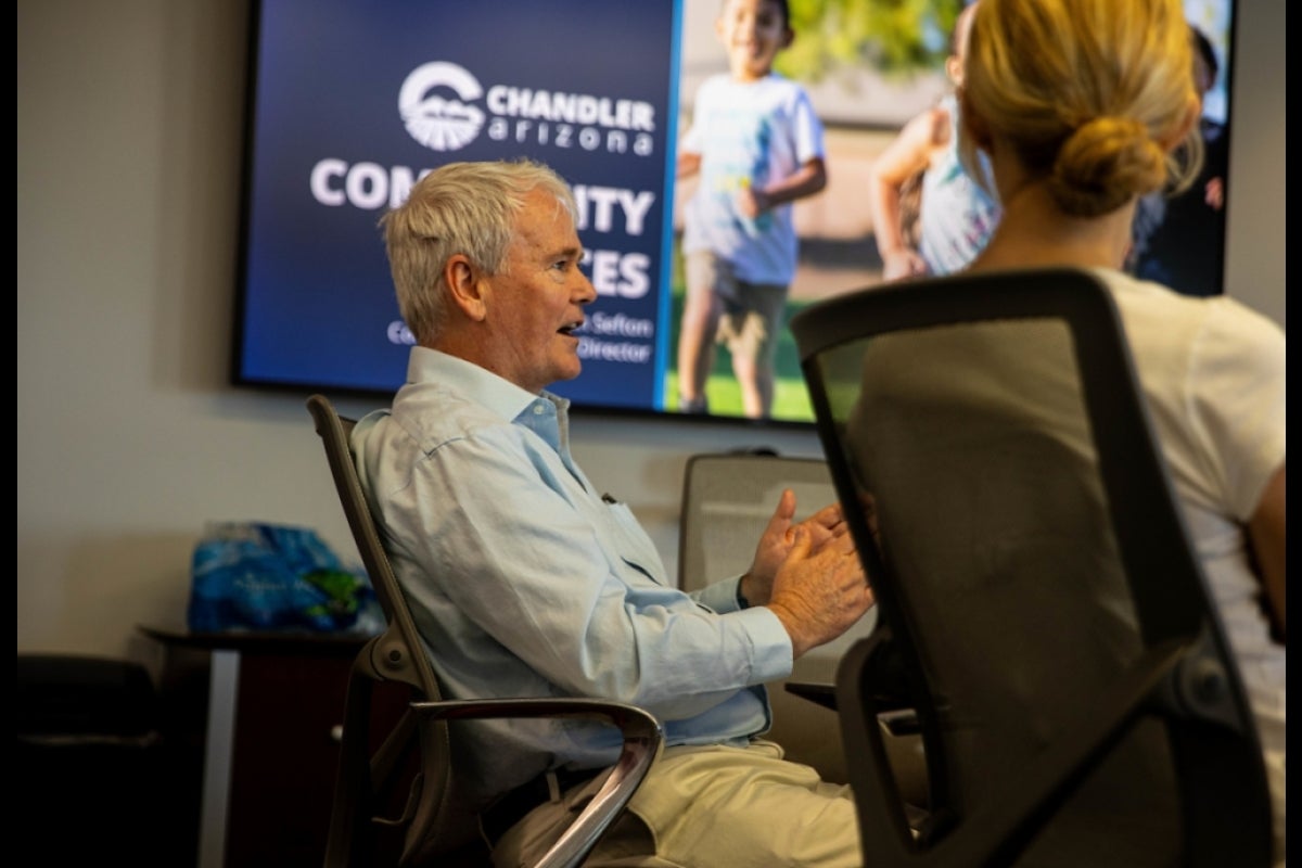 Man seated in a conference room speaking to people seated around him.