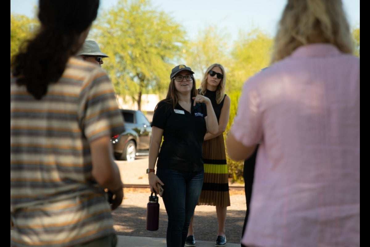 Woman speaking to students gathered in a park.