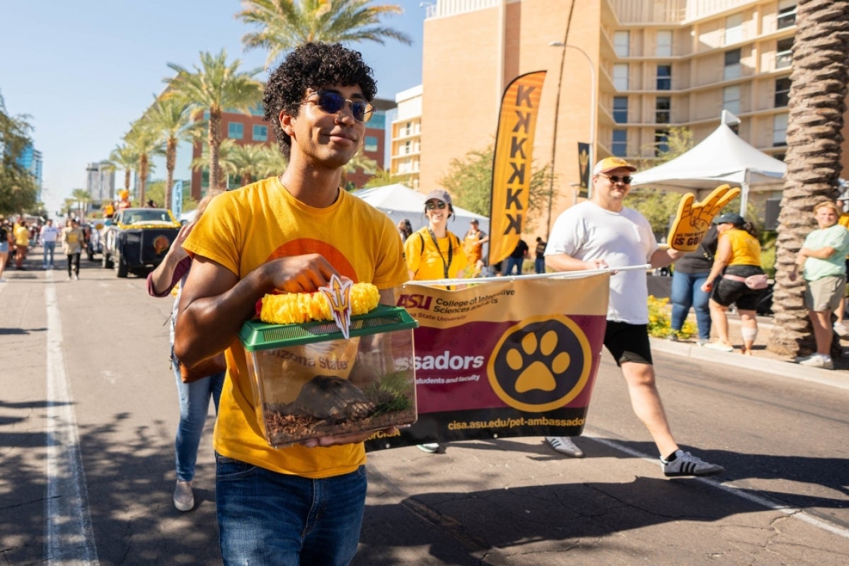 Student carrying reptile in box during Homecoming Parade