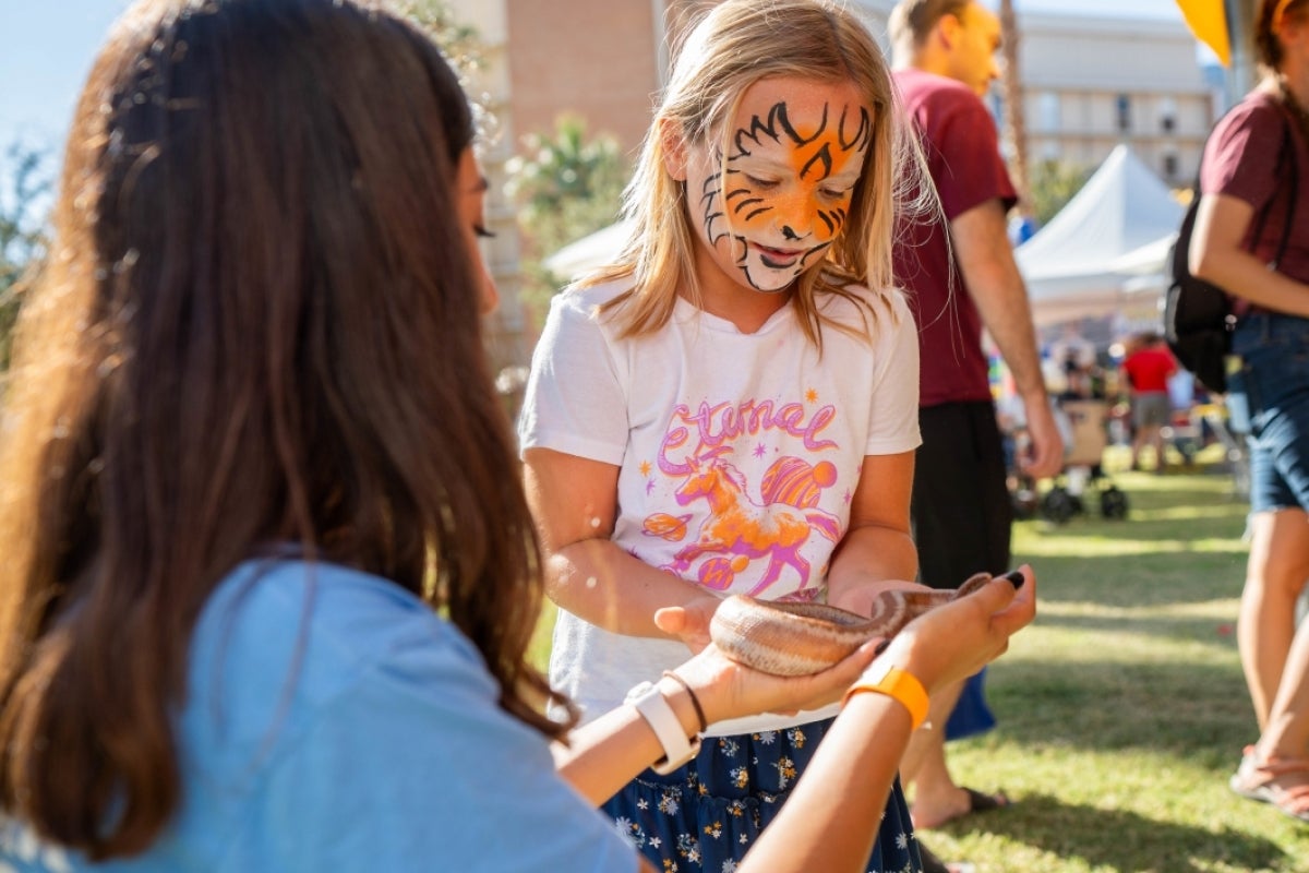 Girl looking at snake during Block Party