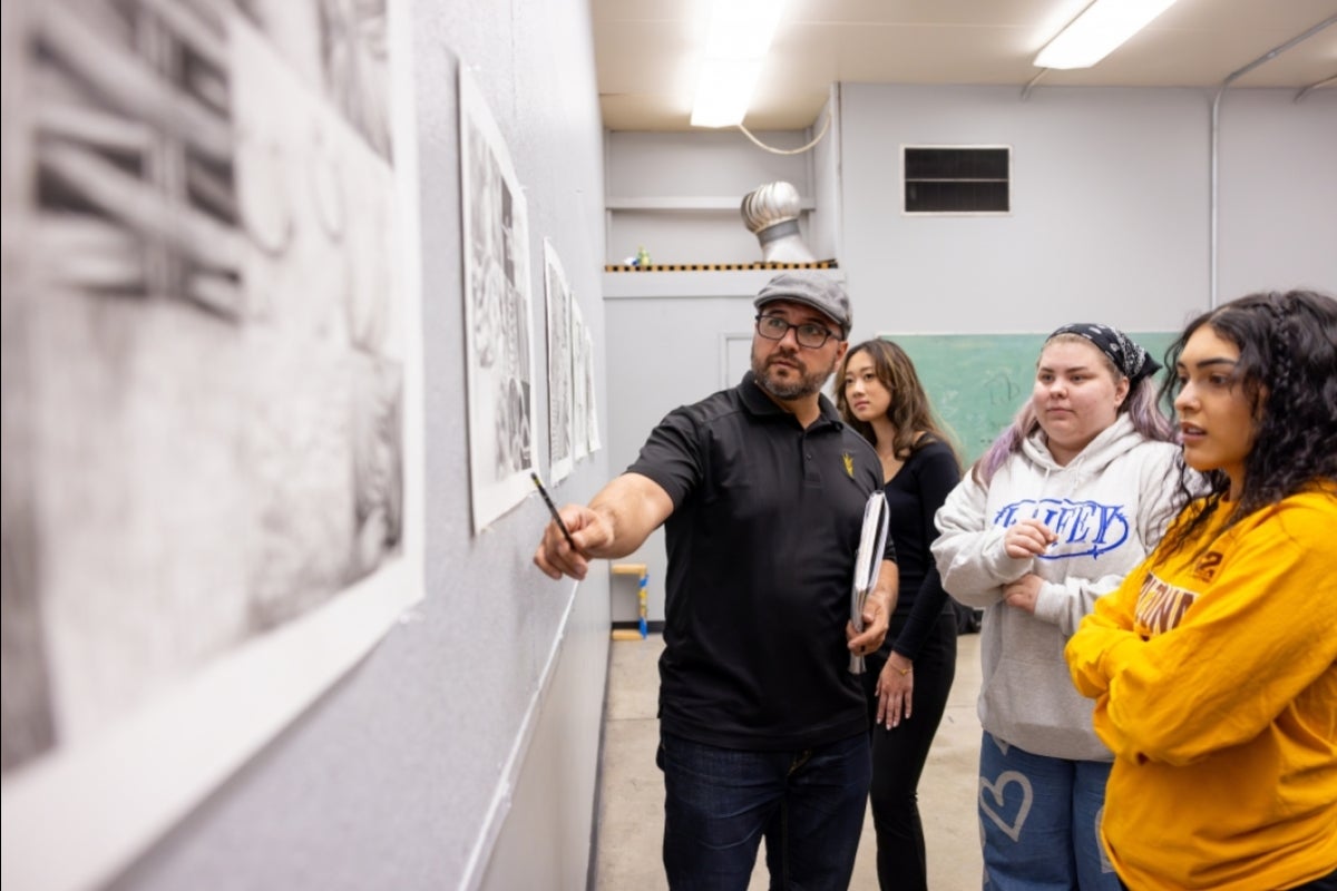 Man points to drawing while talking to students in art class