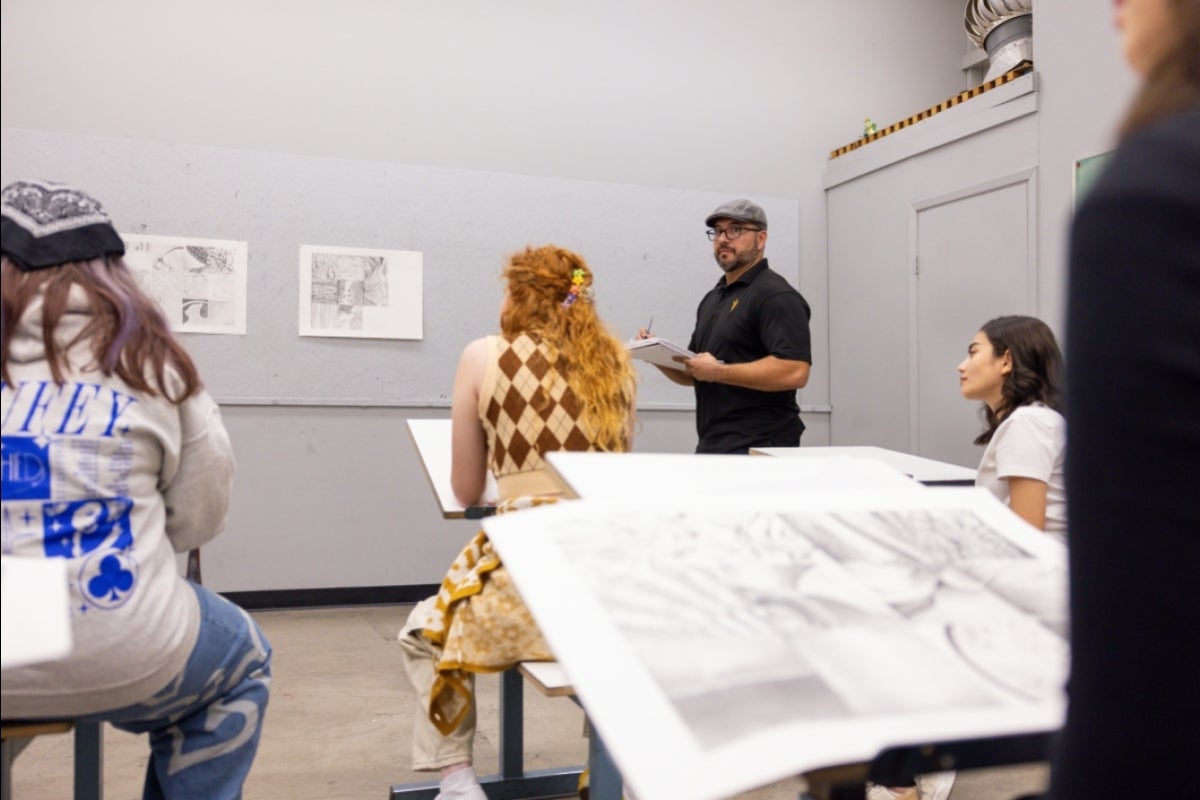 Man standing in front of art class taking notes