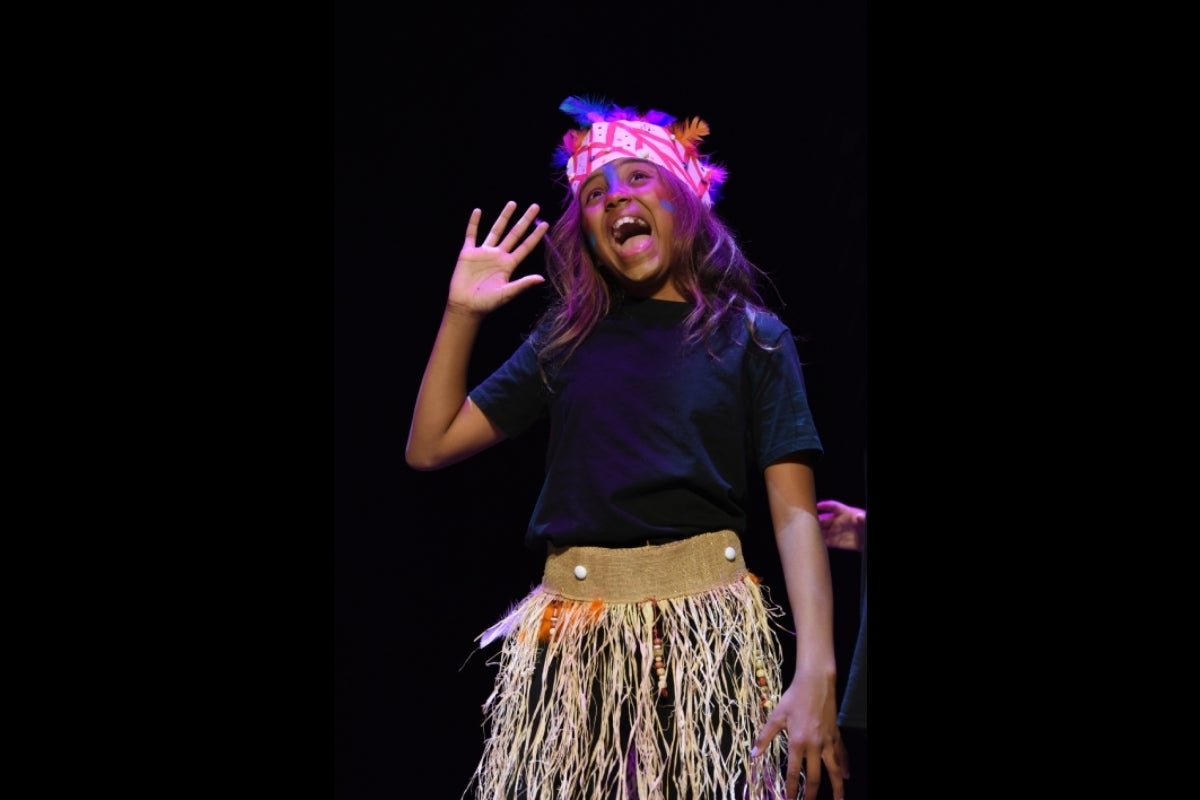 Child in costume performing on stage.