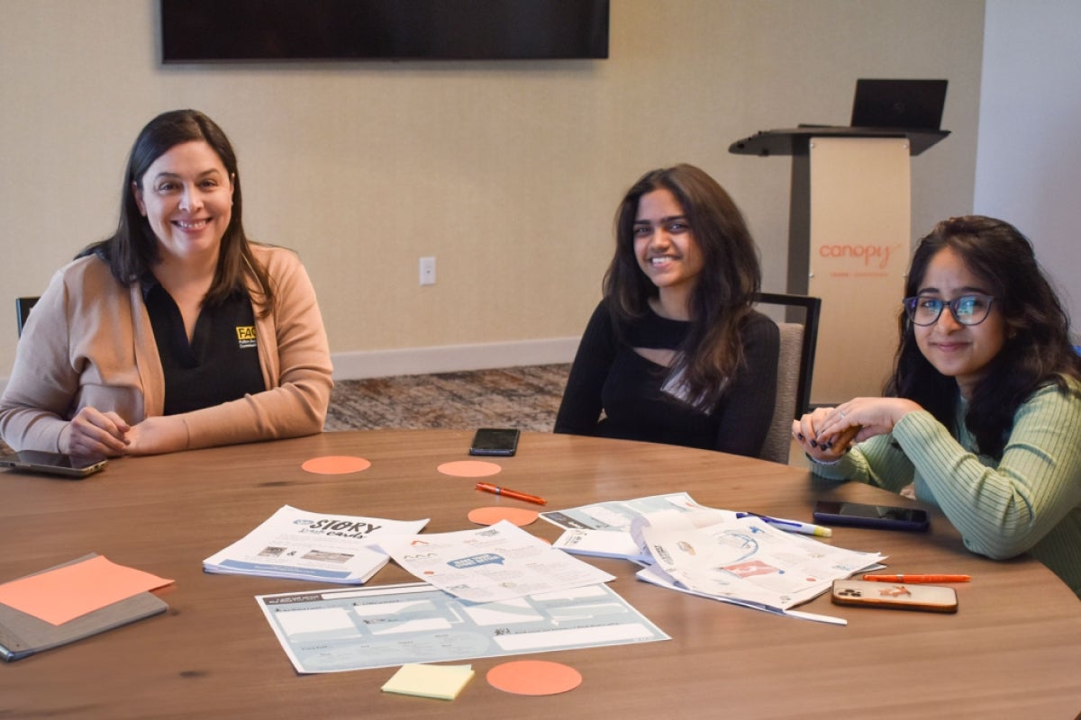 A staff member and two students sit together at a table.