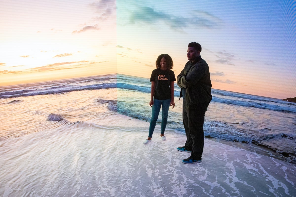 ASU Local students Kara Smith and Bryan Daniels stand in front of Planar Studio screens displaying a beach scene.