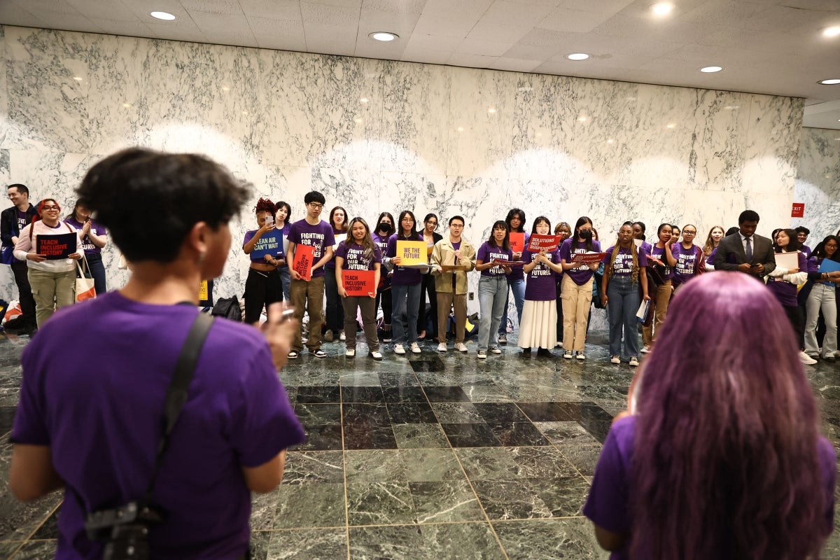 Two people talking to group of students holding signs