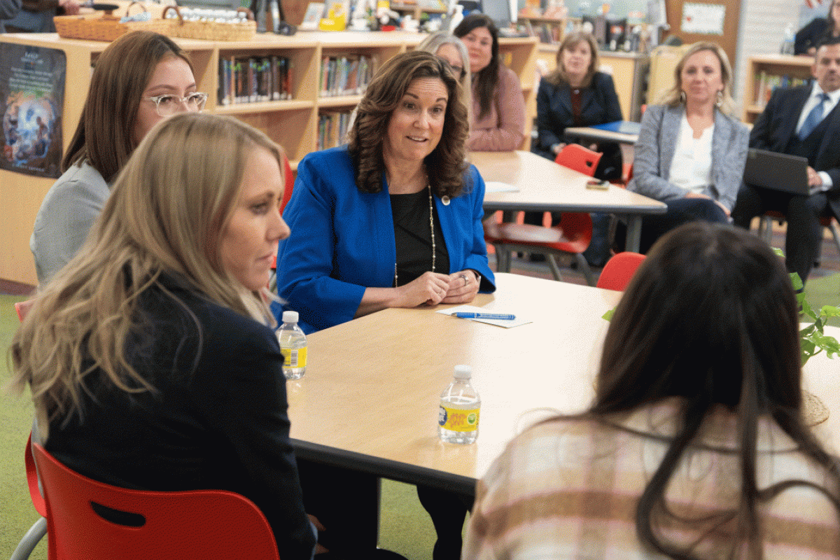 Group of people sitting around table in high school classroom