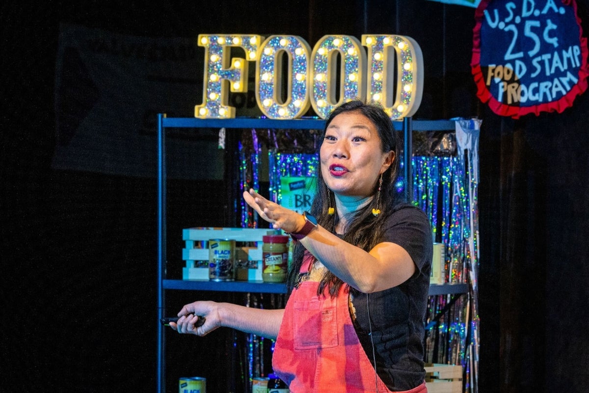 Woman performing onstage in front of a sign that says 