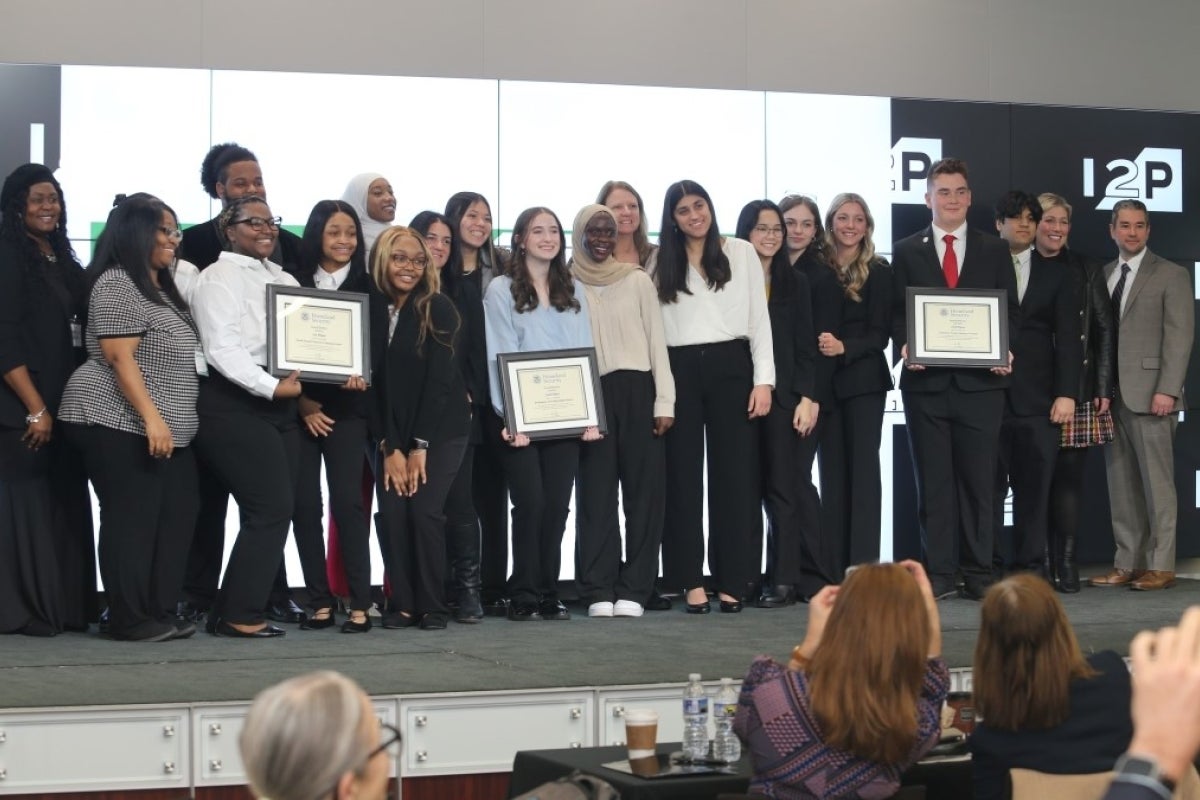 A large group of students posing with three certificates