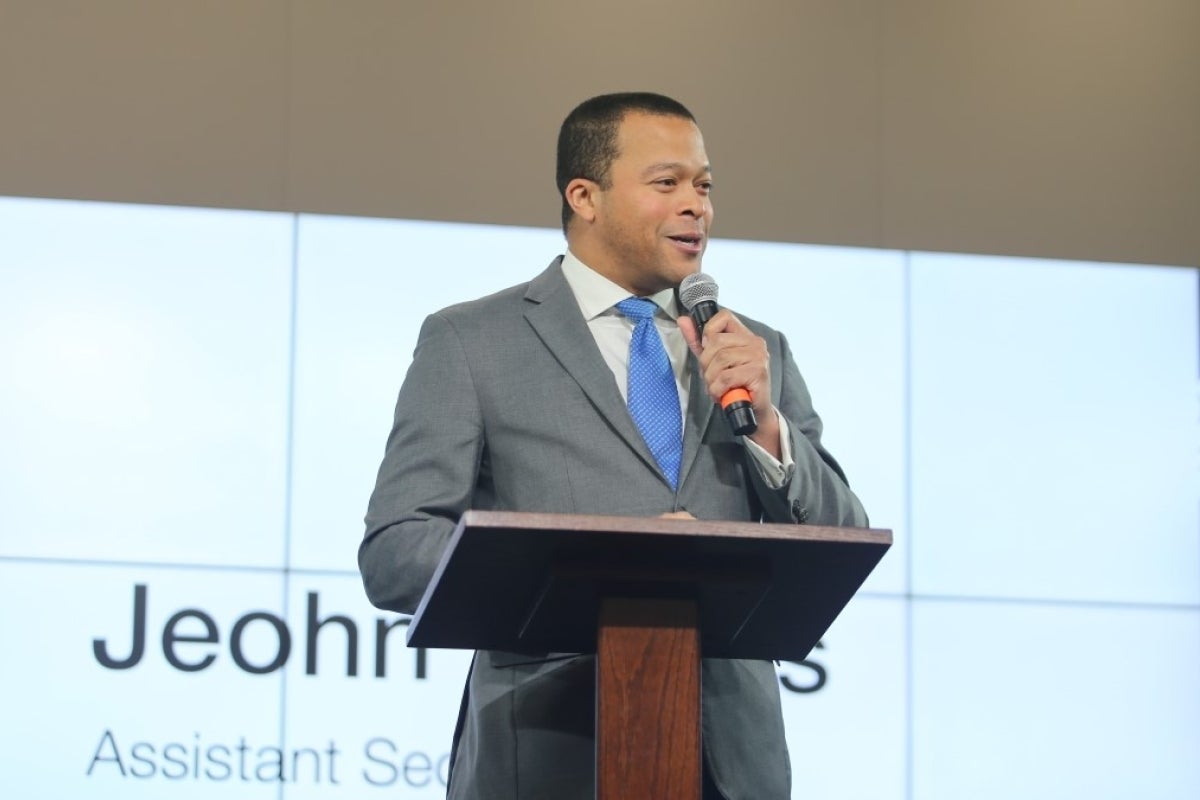 A man in a suit and tie speaks at a lectern to an unseen audience